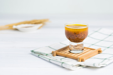 Glass of salad dressing on white table with sesame ingredient