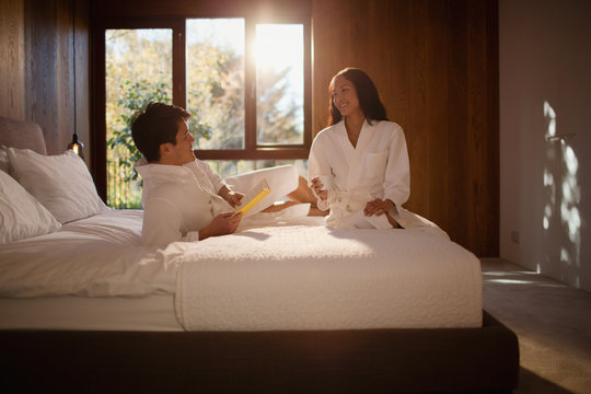 Couple in bathrobes relaxing on hotel bed
