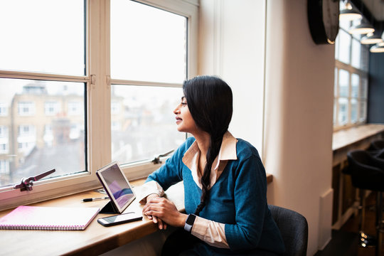 Thoughtful businesswoman working at digital tablet in office window