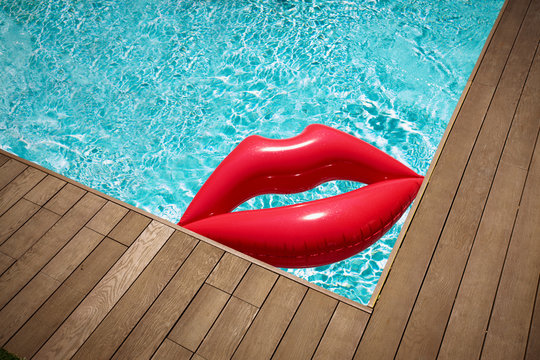 Inflatable lips floating in sunny summer swimming pool