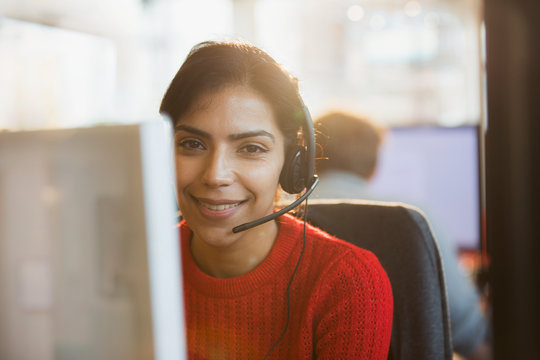 Portrait smiling, confident businesswoman with headset working at computer in office