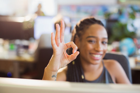 Portrait confident, ambitious businesswoman gesturing OK with hand in office