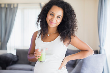 Portrait happy young pregnant woman drinking healthy green smoothie