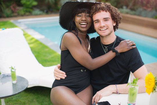 Portrait happy young multiethnic couple relaxing at poolside