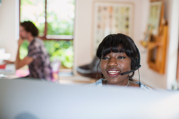 Young woman with headset working from home at computer