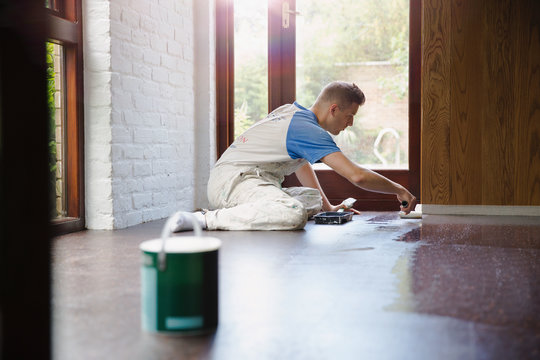 Focused young male construction worker laminating floors at construction site