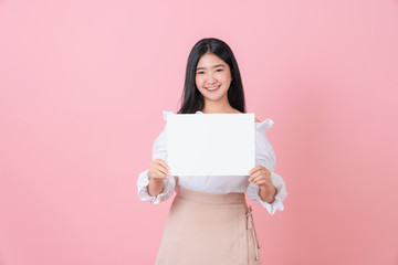 Young Asian woman holding blank paper with smiling face and looking on the pink background. for advertising signs.