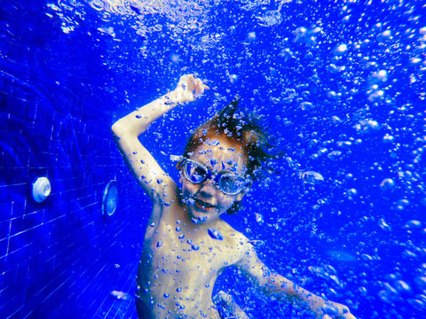 Portrait playful boy swimming underwater in blue swimming pool