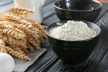 Bowl with flour on dark table
