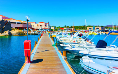 Naklejka premium Old Sardinian Port and marina with ships at Mediterranean Sea in city of Villasimius in South Sardinia Island Italy in summer. Cityscape with Yachts and boats