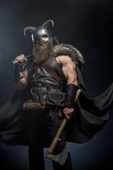 Warrior Viking in full arms with axe and shield on dark background