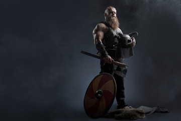 Medieval warrior berserk Viking with tattoo with axes attacks enemy. Concept historical photo - 315258431