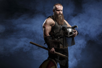 Medieval warrior berserk Viking with axes attacks enemy. Concept historical photo of Scandinavian...