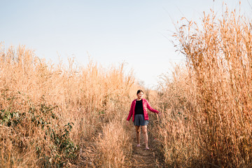 Naklejka na ściany i meble A girl walking on a mountain of brown grass