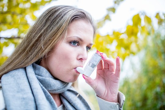 Young woman using inhaler