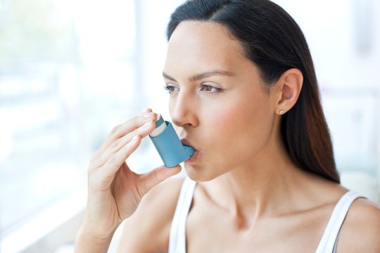 Young woman using inhaler
