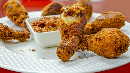 Closeup of hot & crispy, half bitten Chicken leg fry dipped in sauce ready to be eaten.