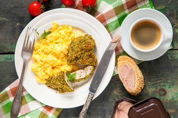 Breakfast - an omelet, chicken fillet in a green breading and coffee on a table. Selective focus. Top view. Copy space.