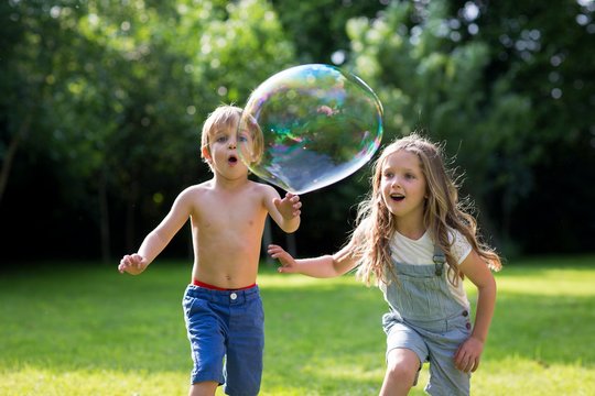 Brother and sister chasing bubbles