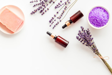Fototapeta na wymiar Lavender cosmetics. Violet spa salt, soap, essence oil on white background top-down copy space