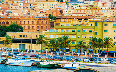 Fototapeta na wymiar Old Sardinian Port with ships at Mediterranean Sea and city of Cagliari, South Sardinia Island in Italy in summer. Cityscape with marina and Yachts and boats in town
