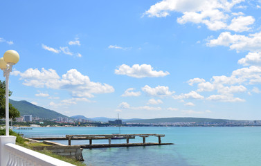 Fototapeta na wymiar Coast of the blue sea. Blue sky with white clouds. In the distance you can see the city.