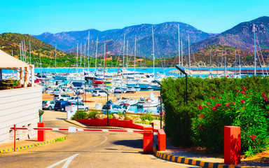 Fototapeta na wymiar Old Sardinian Port and marina with ships at Mediterranean Sea in city of Villasimius in South Sardinia Island Italy in summer. Cityscape with Yachts and boats