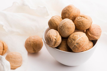 Walnuts in a white ceramic bowl on a white background
