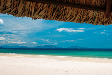 Fototapeta na wymiar Empty white sand beach and parasol, blue sky