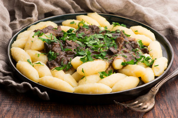 Freshly cooked, Polish traditional potato dumplings serving with mushroom sauce and fresh parsley