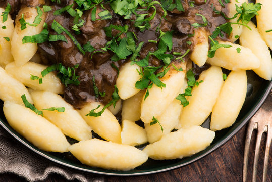 Freshly cooked, Polish traditional potato dumplings serving with mushroom sauce and fresh parsley
