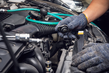 hand of Mechanic check water in car radiator and add water antIfreeze coolant fluid to car radiator at garage , service and maintenance concept . selective focus
