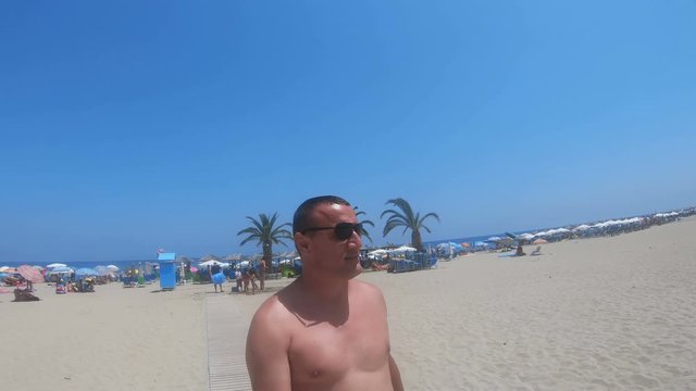 Halkidiki,Greece - 8 July 2018: Handsome man walking on sandy beach on the sunny summer day