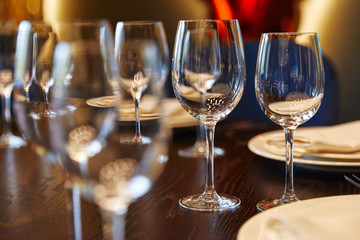 empty glass goblets glasses on a wooden table next to plates