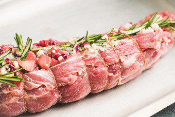 Raw pork loin with fruits, blue cheese and rosemary ready for baking. Selective focus. Shallow depth of field.