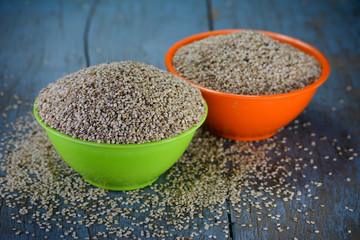 Sesame seeds in bowls on wooden background