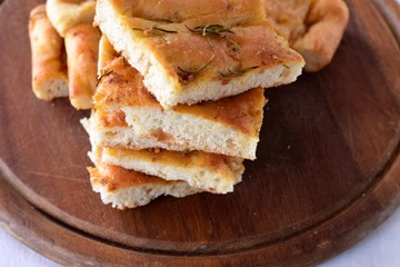 Homemade Italian Focaccia Modenese, with rosemary and olive oil on a rustic wooden background.