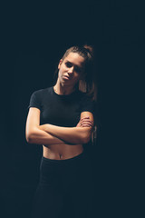 Defiant athletic girl on a dark background. Dramatic portrait. Toned.