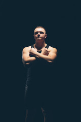Athlete bodybuilder on a dark background. Dramatic portrait.
