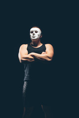 Athlete bodybuilder on a dark background. Dramatic portrait. The masked man.