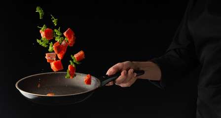 sea ​​or ocean food. Roasting in a pan of salmon, with salted parsley. Useful and tasty food. Culinary and gastronomy. Freezing in motion. On a black background, horizontal photo.