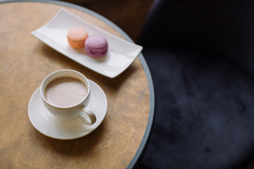 Tasty chocolate milk  and berry macaroons on wooden table.
