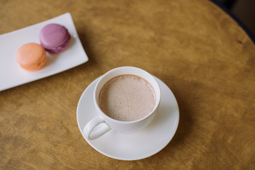 A cup of coffee with milk and berry macaroons.