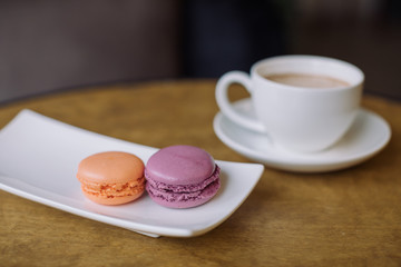 Berry macaroons and mug of hot cocoa on wooden table.