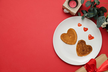 Pancakes heart shaped on white plate, composition for valentines day with food. Space for text