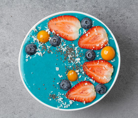 Healthy blue spirulina smoothie bowl with blueberry, strawberries, physalis, Chia seeds and bananas.