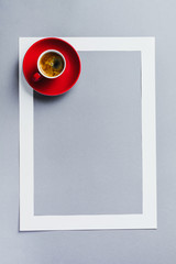 Red cup with coffee and paper frame on classic blue background. Morning minimal concept.