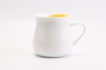 A group of yellow peeled mung bean stay in white mug