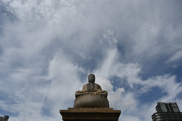A buddha statue in front of a cloudy, blue sky in Osaka-Japan.