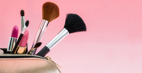 Make-up cosmetic products bag against pink background, copy space